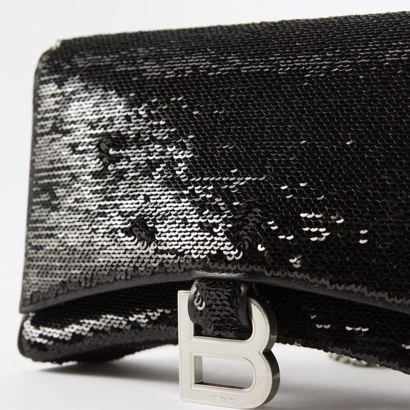 Black sequin clutch with a silver clasp on a white background