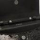 Close-up of a black handbag with 'Balenciaga' branding on a textured surface.