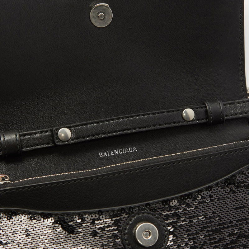 Close-up of a black handbag with 'Balenciaga' branding on a textured surface.