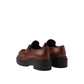 Brown leather shoes with thick black soles on a light gray background