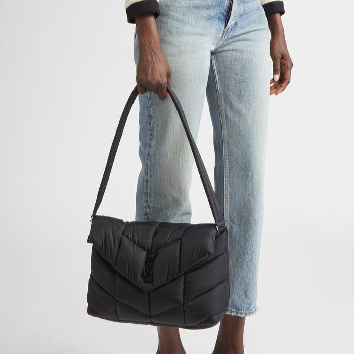 Person holding a black puffer bag against a white background