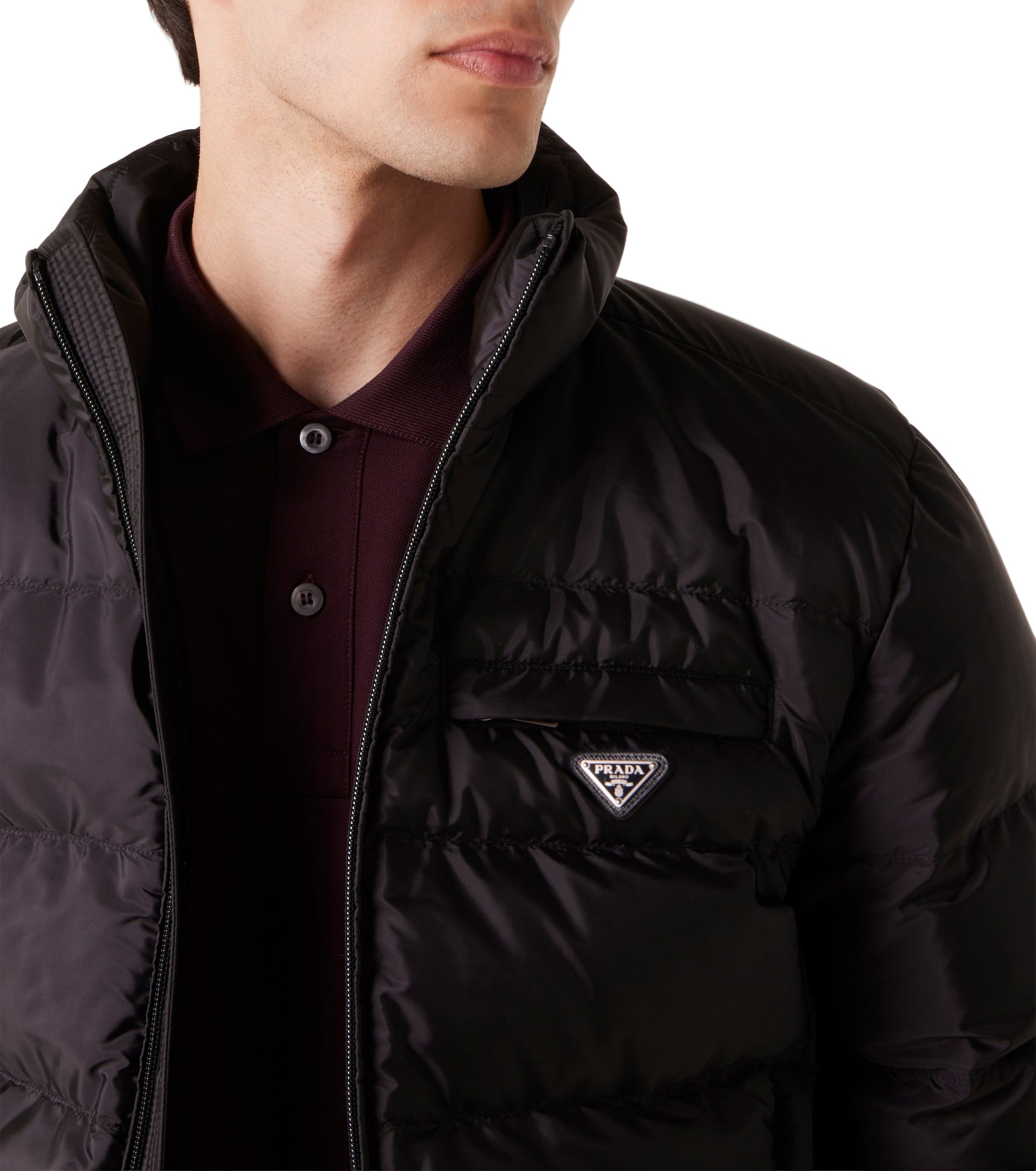 Person wearing a black puffer jacket with a brand logo on a light gray background
