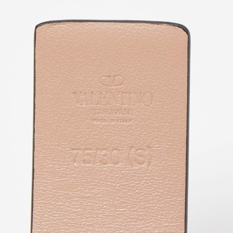 Close-up of a beige leather product with 'Valentino' branding on a light gray background