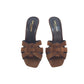 Pair of brown suede sandals with a bow design on a white background