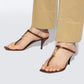 Brown high-heeled sandals worn with beige pants on a white background