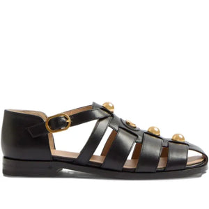 Black sandal with gold accents on a white background