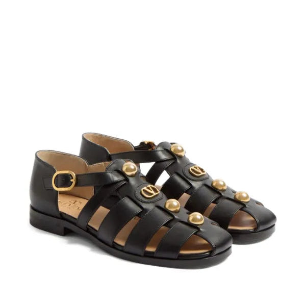 Black sandals with gold buckles on a white background
