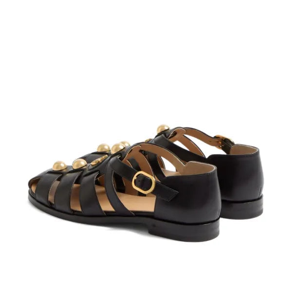 Black sandals with gold accents on a white background