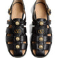 Black sandals with pearl embellishments and gold logo on a white background