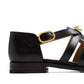 Black sandal with a gold buckle on a white background