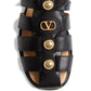 Black sandal with gold accents featuring a logo on a white background