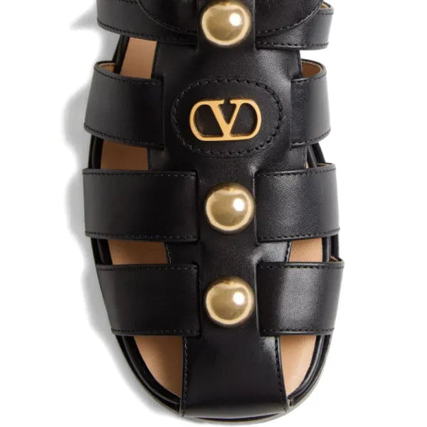Black sandal with gold accents featuring a logo on a white background