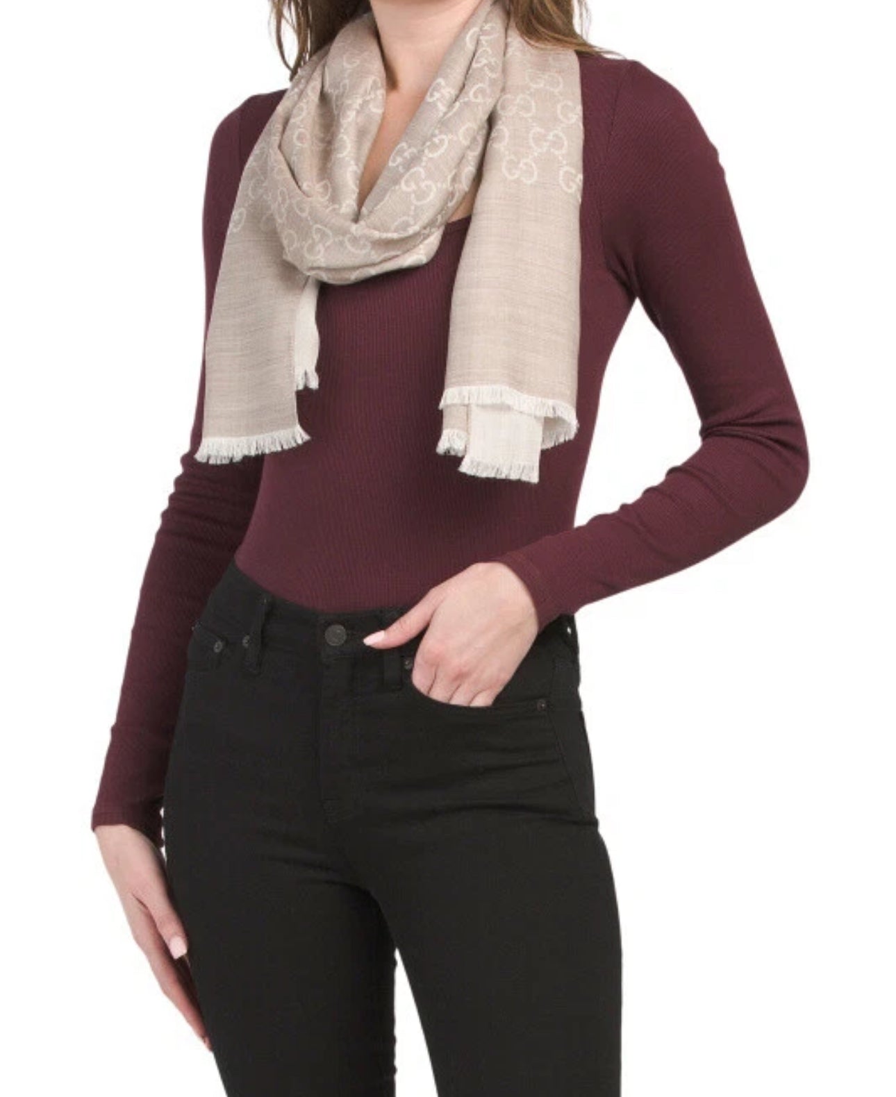 Person wearing a burgundy sweater and black pants with a beige scarf on a white background