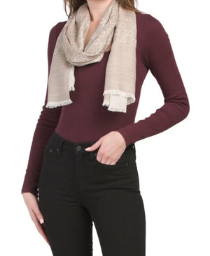 Person wearing a burgundy sweater and black pants with a beige scarf on a white background