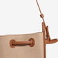 Close-up of a beige handbag with brown leather straps on a white background