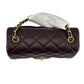 Brown quilted handbag with gold chain strap on a light gray background