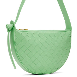 Green bottega Veneta woven handbag with a strap on a white background