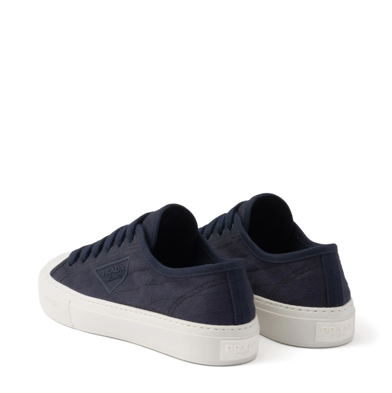 Pair of navy blue sneakers with white soles on a white background