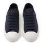Pair of navy blue luxury Prada sneakers with white soles on a white background