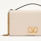 Beige handbag with gold chain and logo on a light beige background
