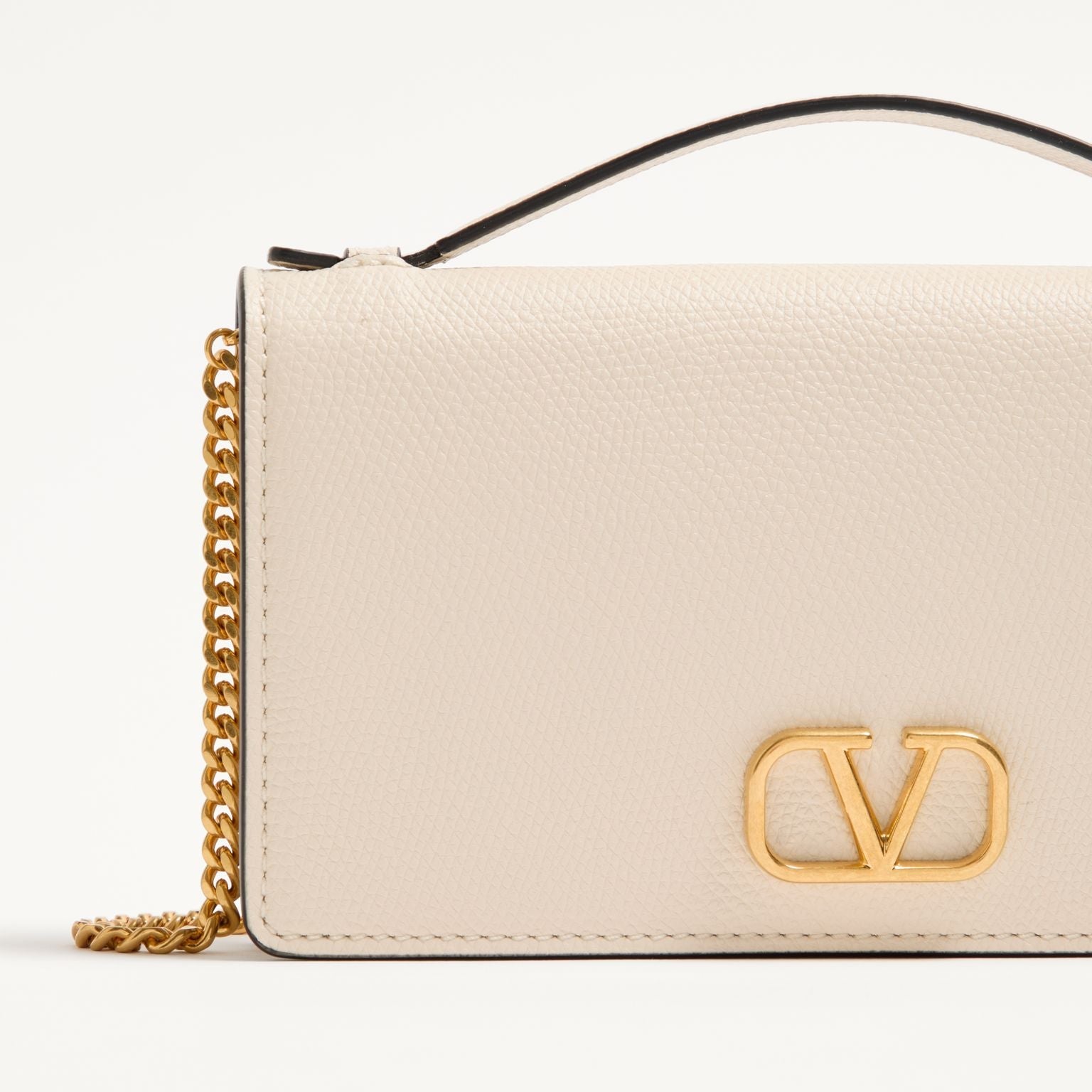 Beige handbag with gold chain and logo on a light beige background