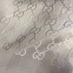 Close-up of a textured Gucci fabric with a repeated pattern.