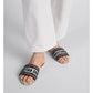 Person wearing black sandals with 'Christian Dior' branding on a light gray background