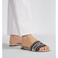 Black slide sandal with 'Christian Dior' logo worn by a person on a light gray background