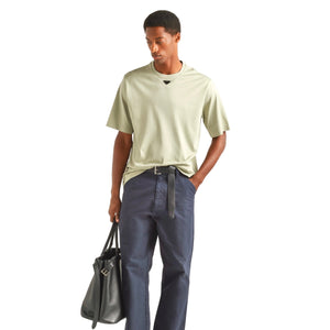 Man wearing a beige t-shirt, dark blue jeans, and black shoes on a white background