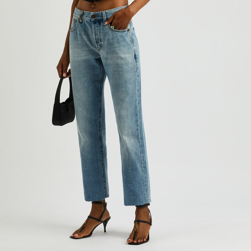 Person wearing a black sleeveless top and light blue jeans on a plain background