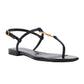 Black sandal with thin straps and gold accents on a white background