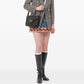 Person wearing a plaid blazer, patterned skirt, and black rain boots on a white background