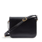 Black leather handbag with a gold buckle on a white background