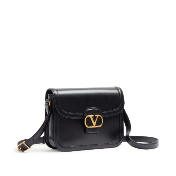 Black handbag with a gold clasp on a white background