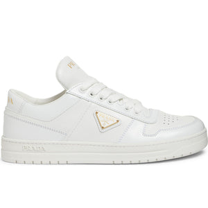 White sneakers with a gold triangle logo on a white background