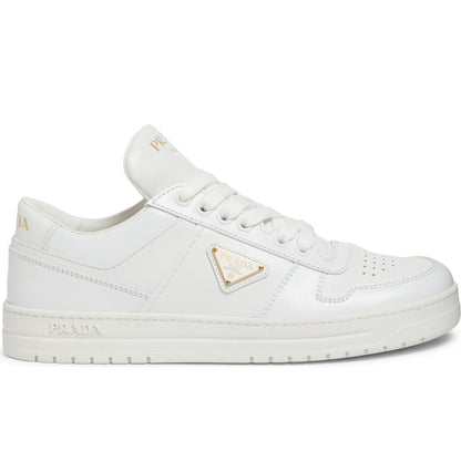 White sneakers with a gold triangle logo on a white background