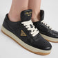 Black Prada sneakers with white laces on a light gray background
