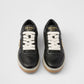 Black Prada sneakers with white laces on a light gray background