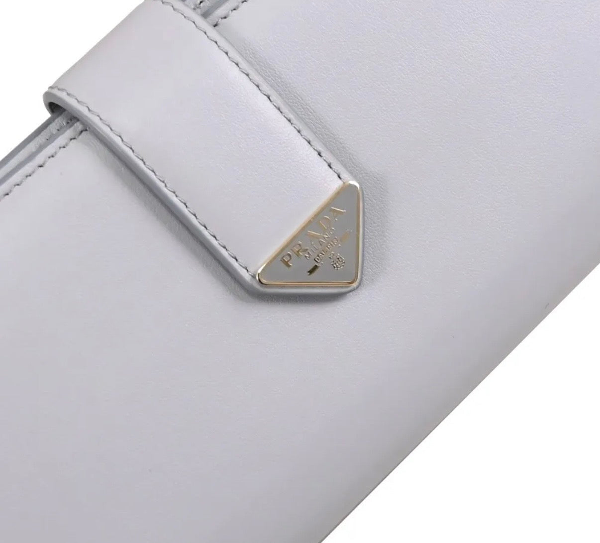 Close-up of a light gray wallet with a brand logo on a white background
