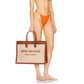 Woman in orange bikini holding a 'Rive Gauche' bag on a white background