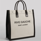 Black and beige handbag with 'Rive Gauche Saint Laurent' text on a gray background