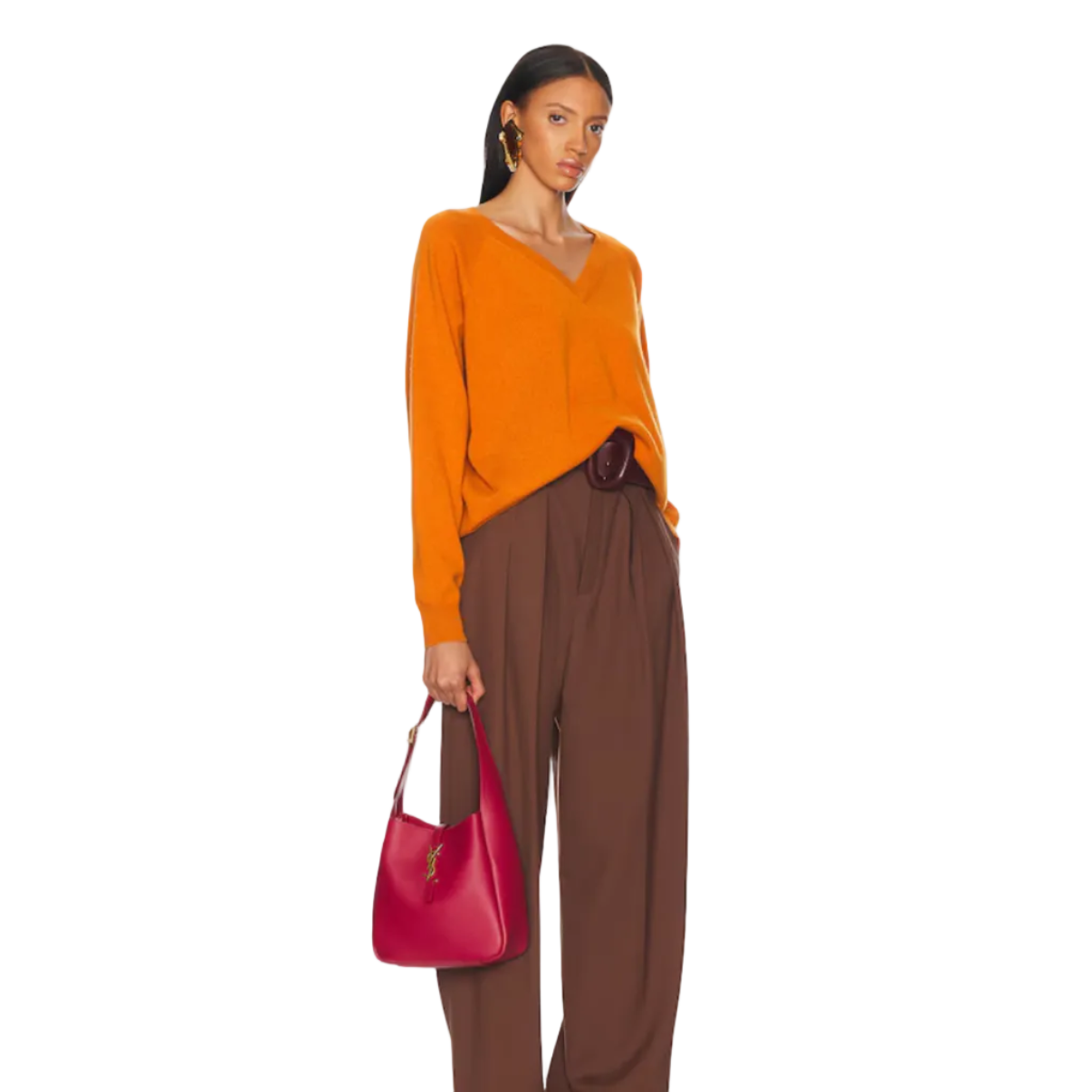 Woman wearing an orange top and brown pants holding a red bag on a white background