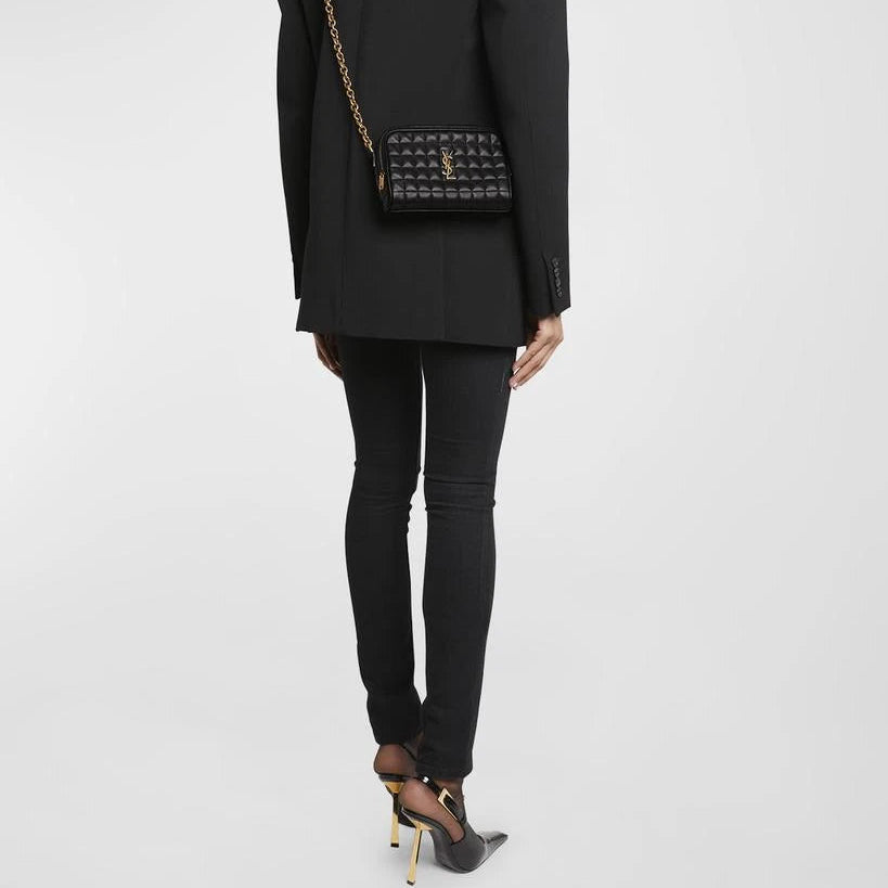 Person wearing a black outfit with a patterned handbag on a white background