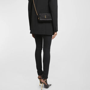 Person wearing a black outfit with a patterned handbag on a white background