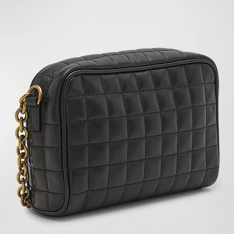 Black quilted handbag with a gold chain on a light gray background