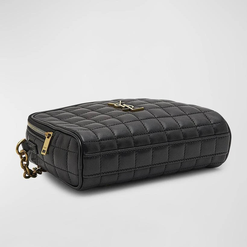 Black quilted handbag with gold chain on a light gray background