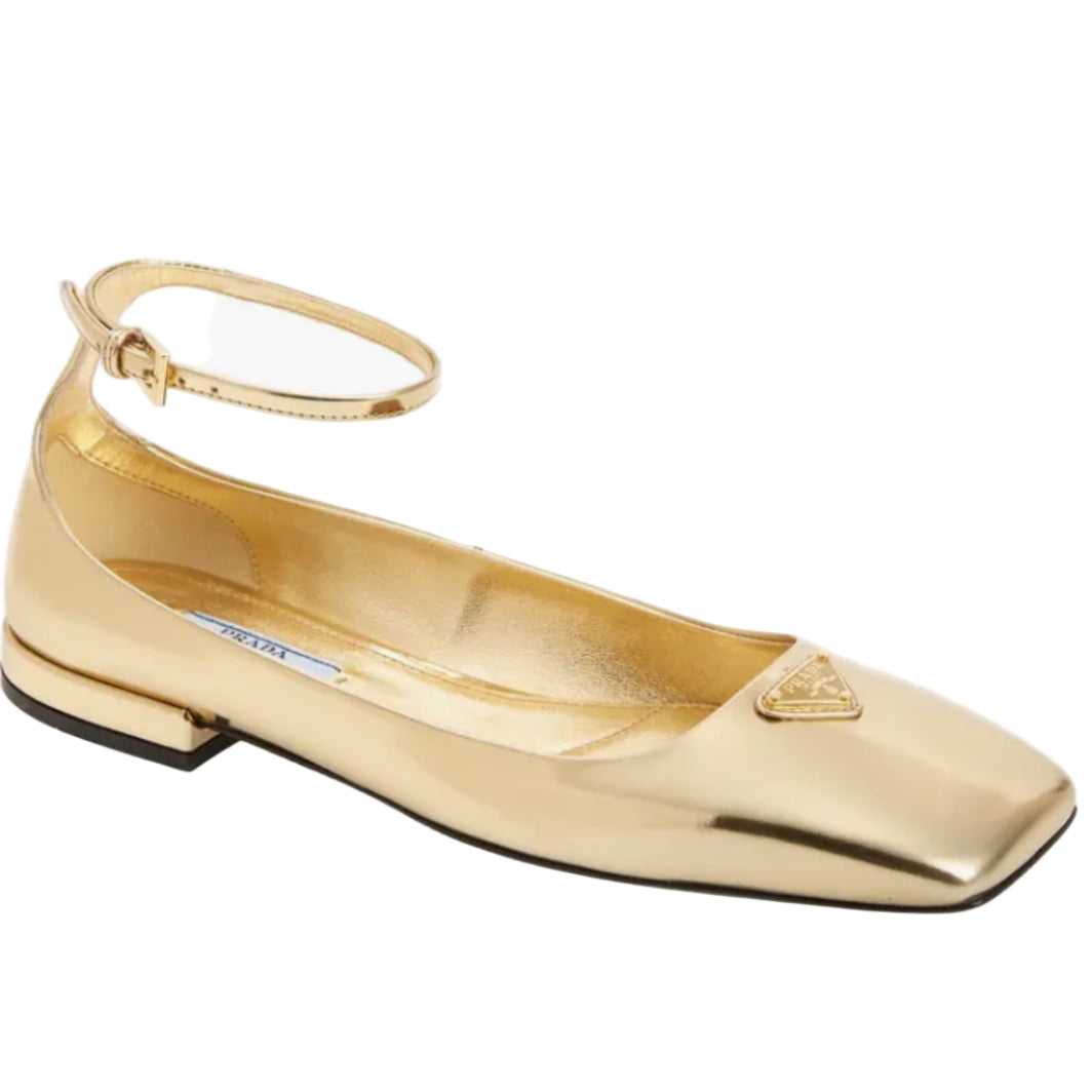 Gold flat shoe with a brand logo on a white background