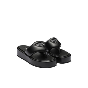 Black sandals with a brand logo on a light gray background