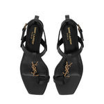 Black high-heeled sandals with gold logo on a white background