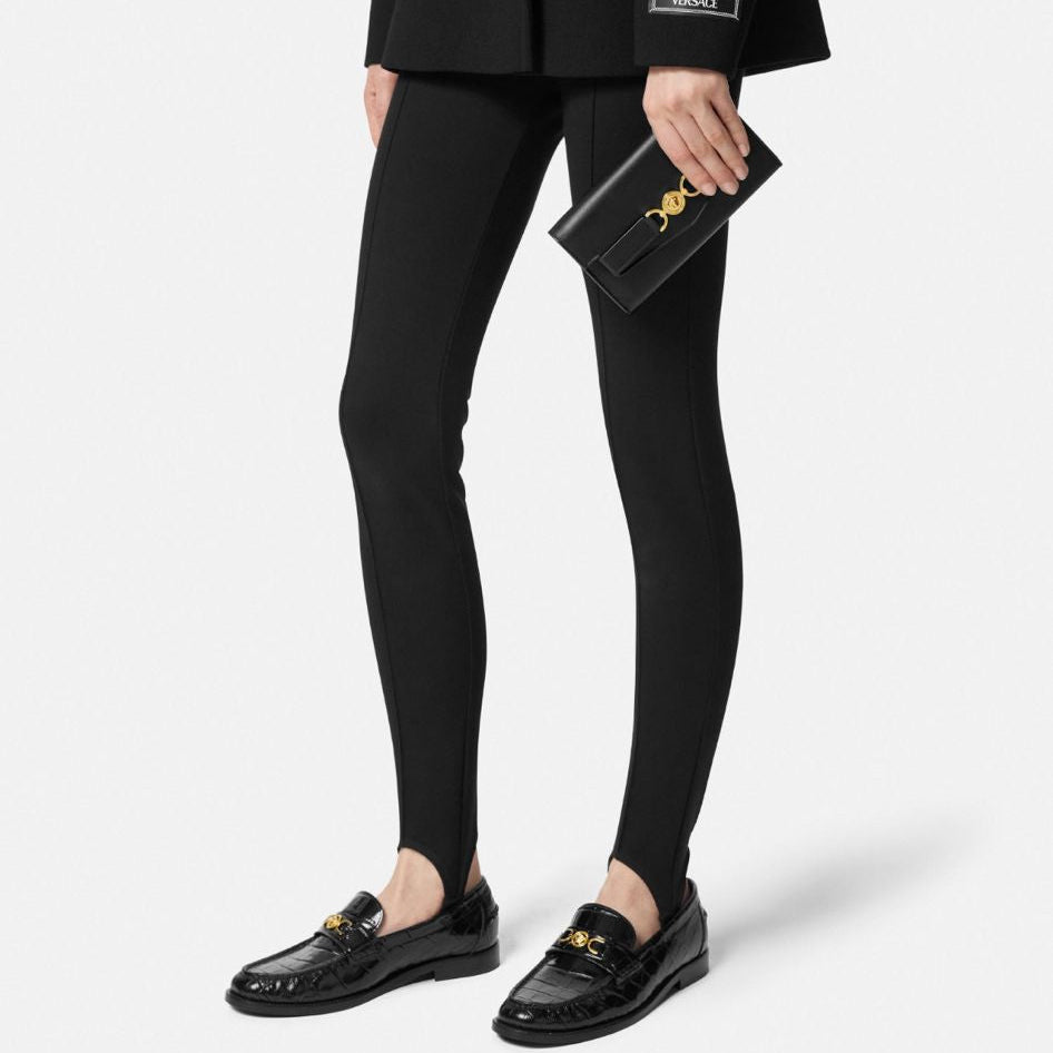 Person wearing a black suit with gold buttons on a white background